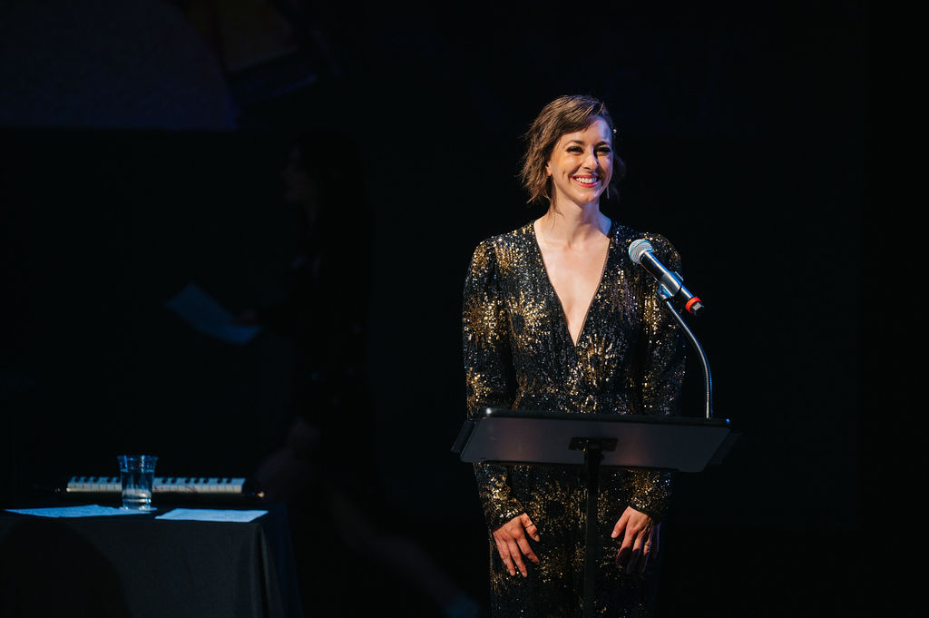 <p>TPC alum and Round House Teaching Artist EmmaLou Joy speaking at the <em>Broadway in Bethesda </em>Gala. Photo by Cameron Whitman Photography. </p>
